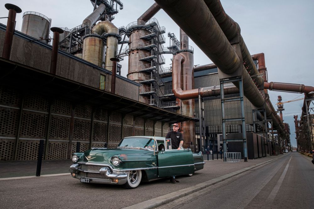 Ein Oldtimer steht geparkt unter den Gebläserohren der Hochöfen auf Belval