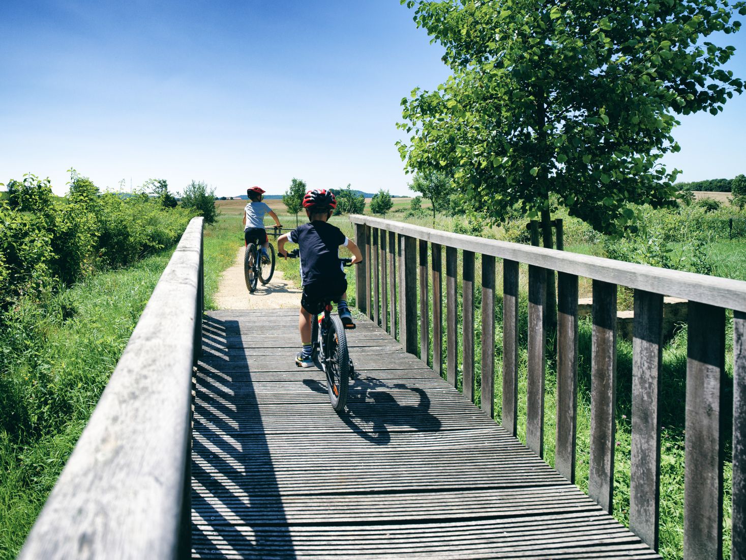 Deux enfants sur leurs VTT, roulant sur un pont en bois