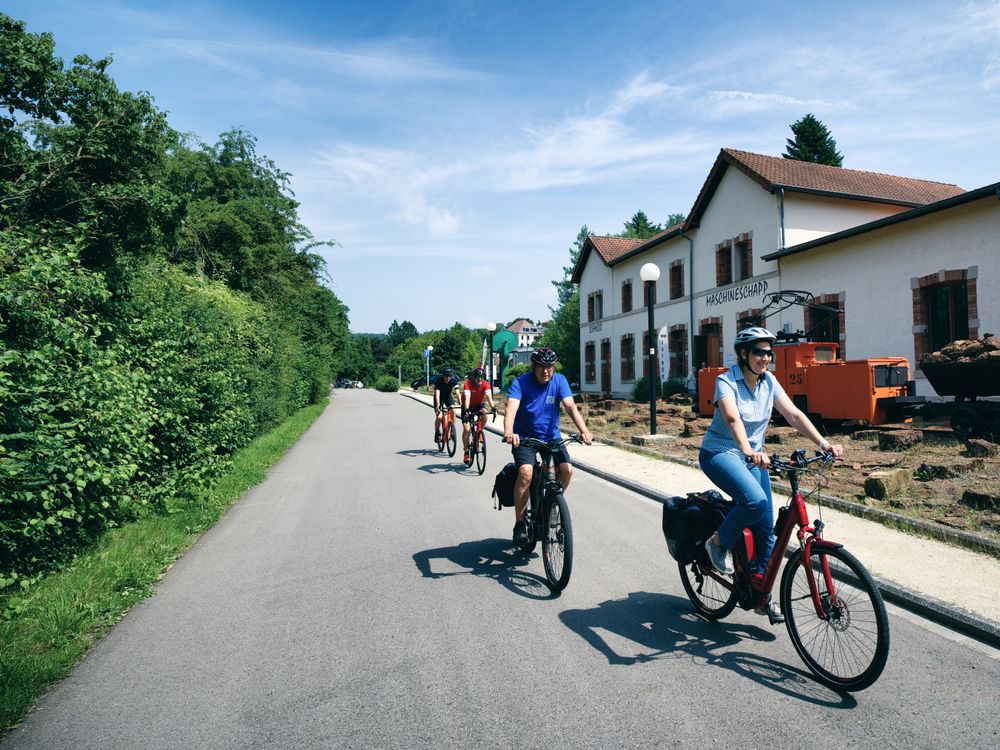 Plusieurs cyclistes en route devant le Musée des Mines à Rumelange